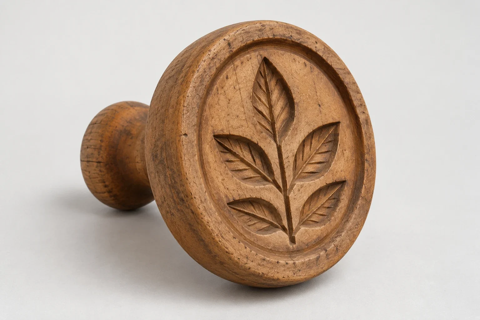 AI-generated round wooden butter stamp with recessed leaf carving and a short rear handle.