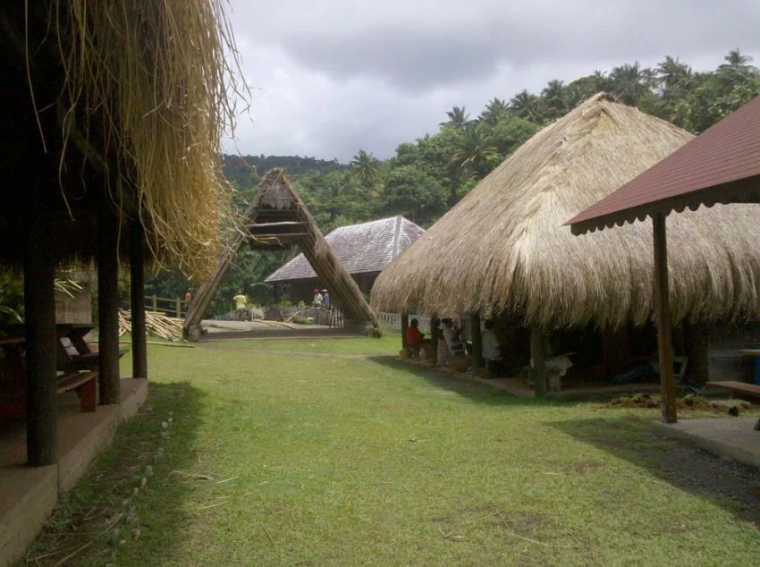 Thatched structures and grassy paths at Kalinago Barana Autê cultural village in Dominica, as pictured in the 7toucans listing