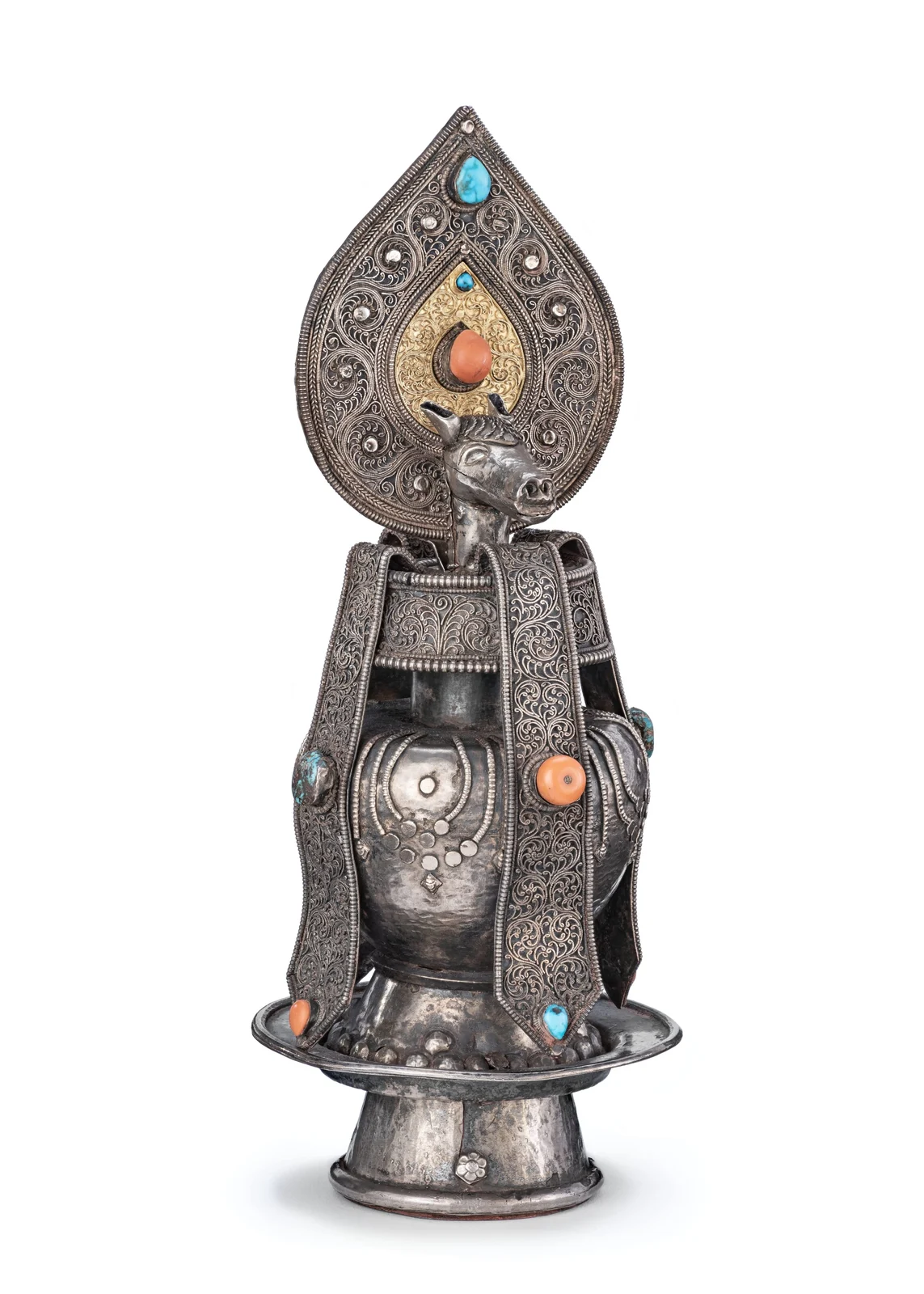 Silver-and-gold filigree ritual vase with a projecting horse head beneath a tall teardrop-shaped finial, inset with turquoise and coral; the complete vessel and pedestal are visible.