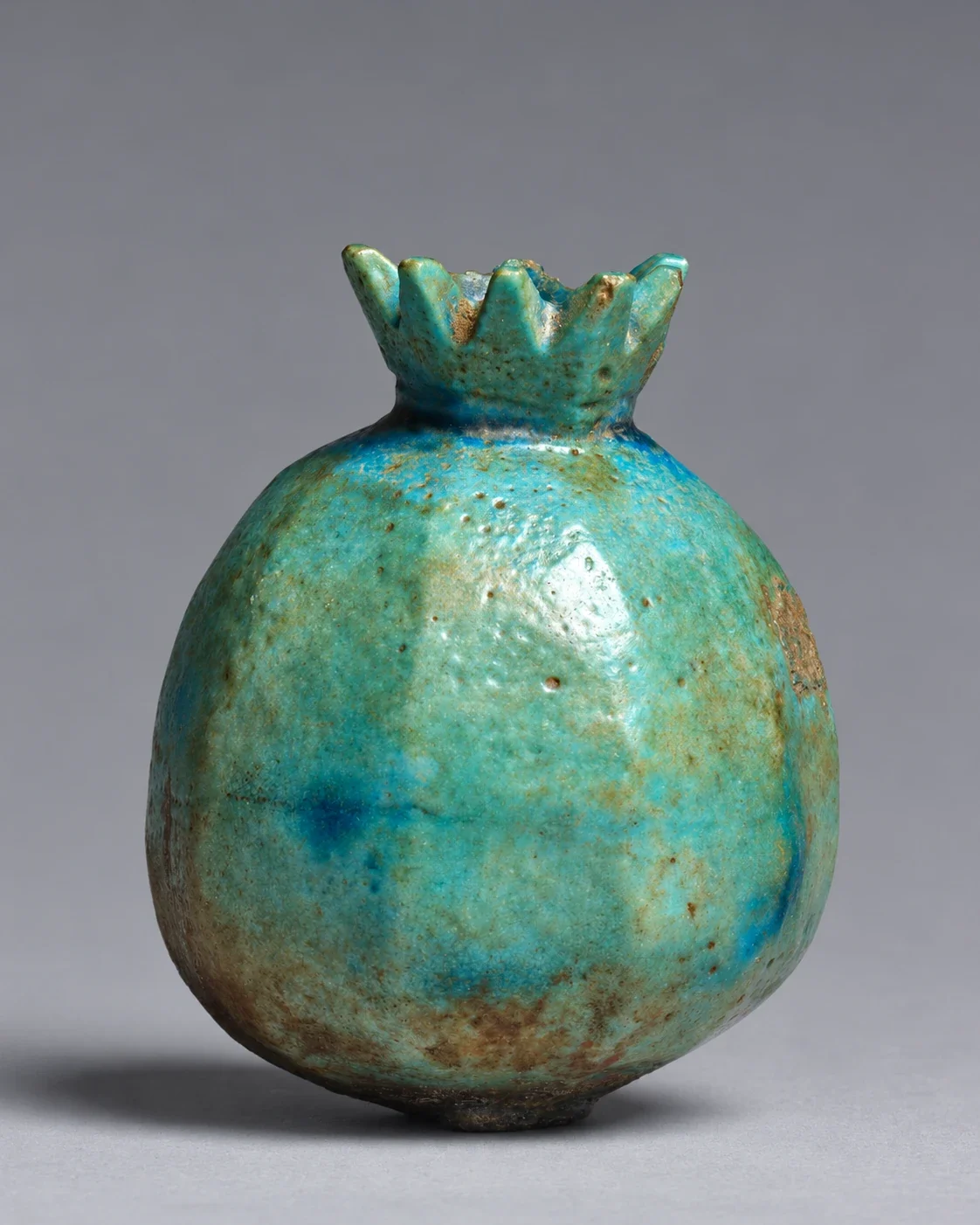 Blue faience pomegranate flask with a toothed calyx.