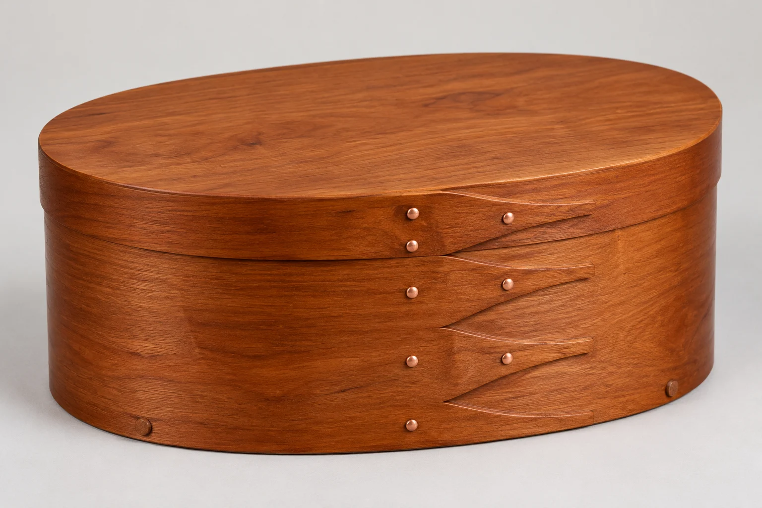 Oval wooden box with finger joints.