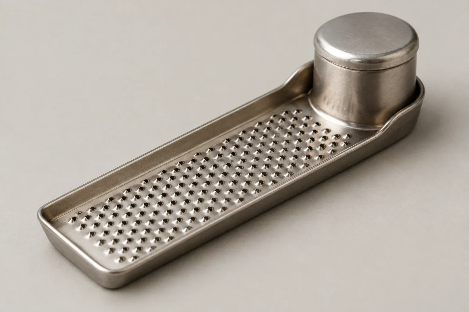 Tin nutmeg grater with rasp and capped cylinder.