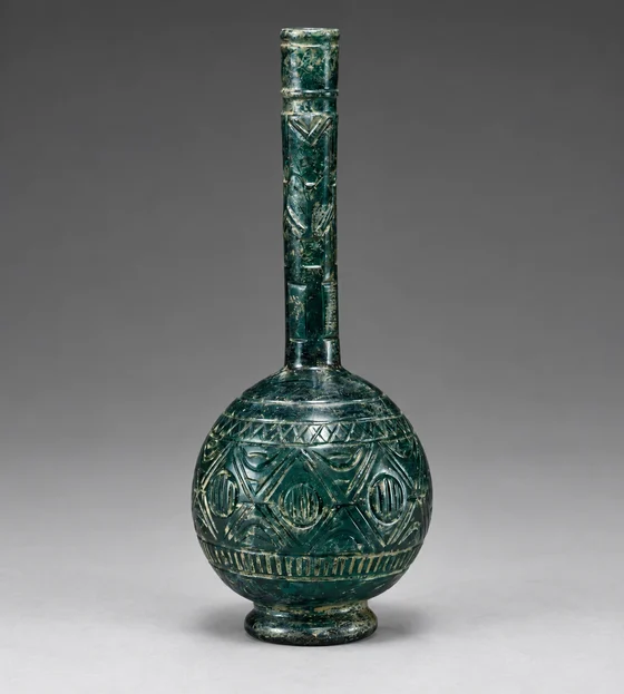 Long-necked blue-green bottle with carved bands.