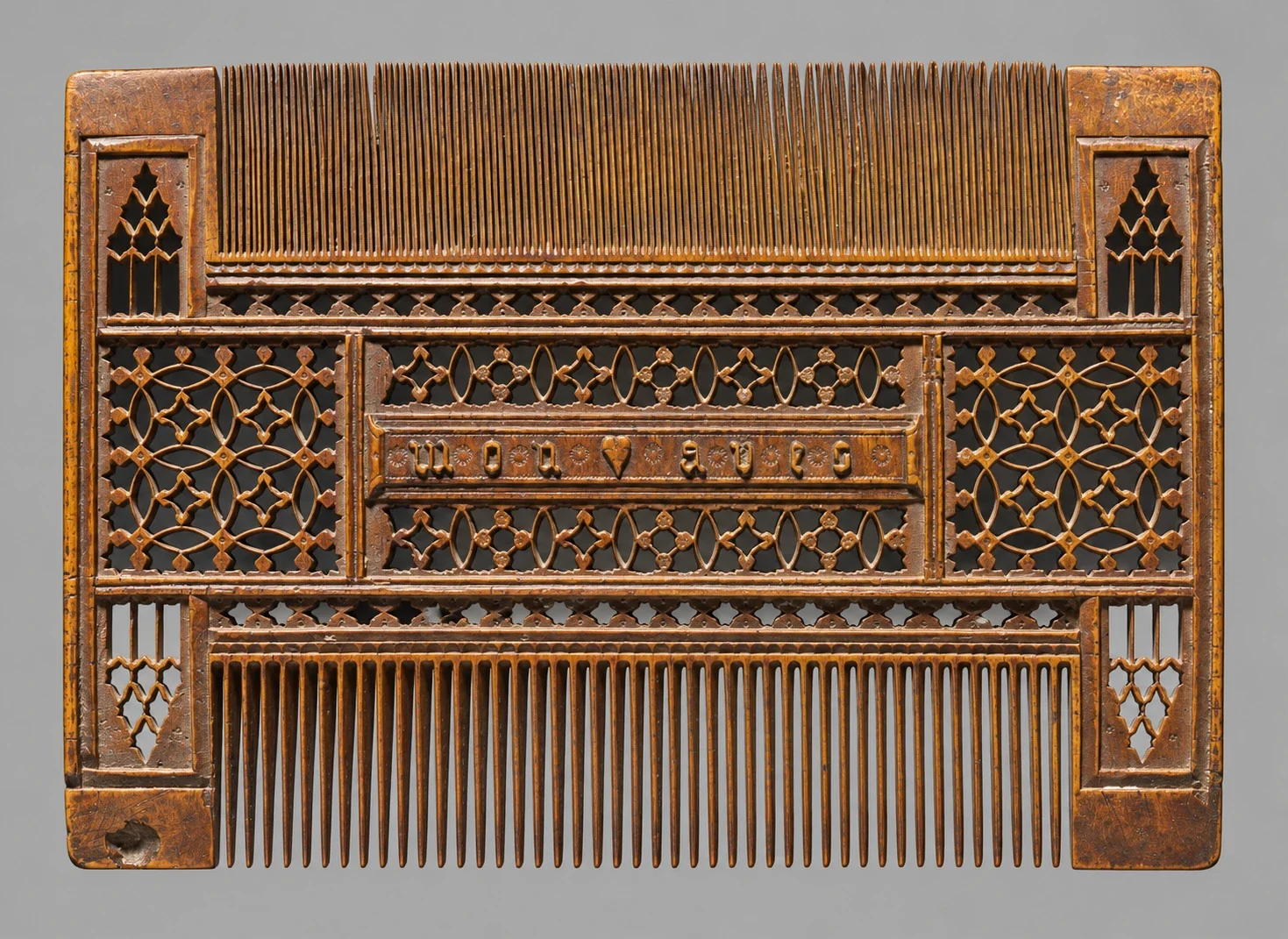 Double-sided boxwood comb with pierced tracery.