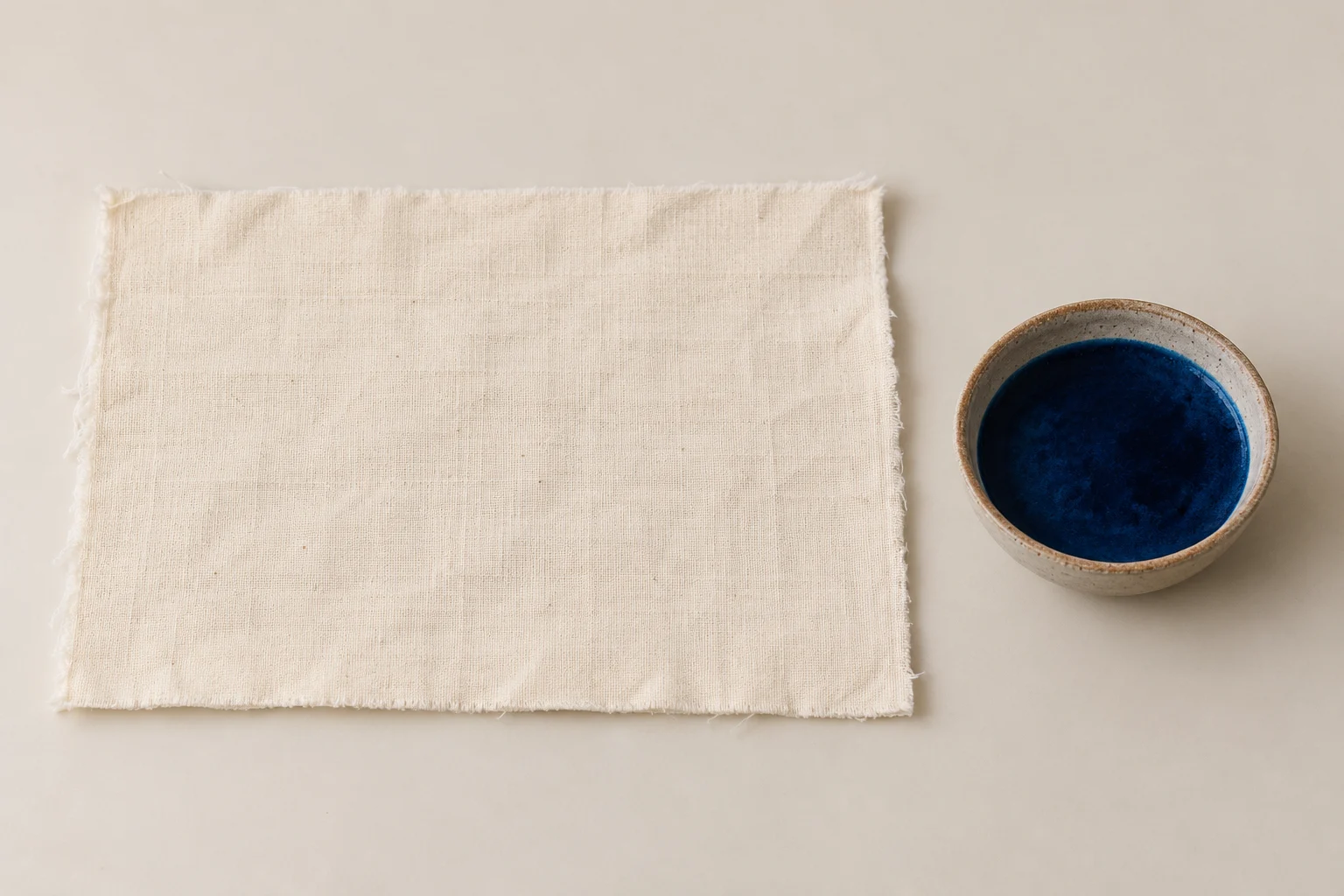 Plain cotton rectangle beside a dye bowl.