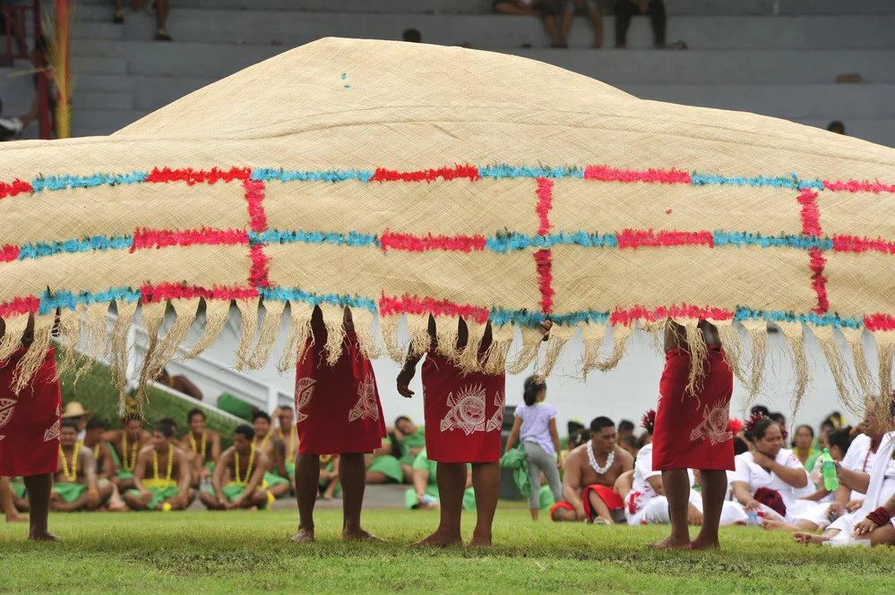 A Samoan ʻie tōga fine mat held out before spectators, National Park Service photograph