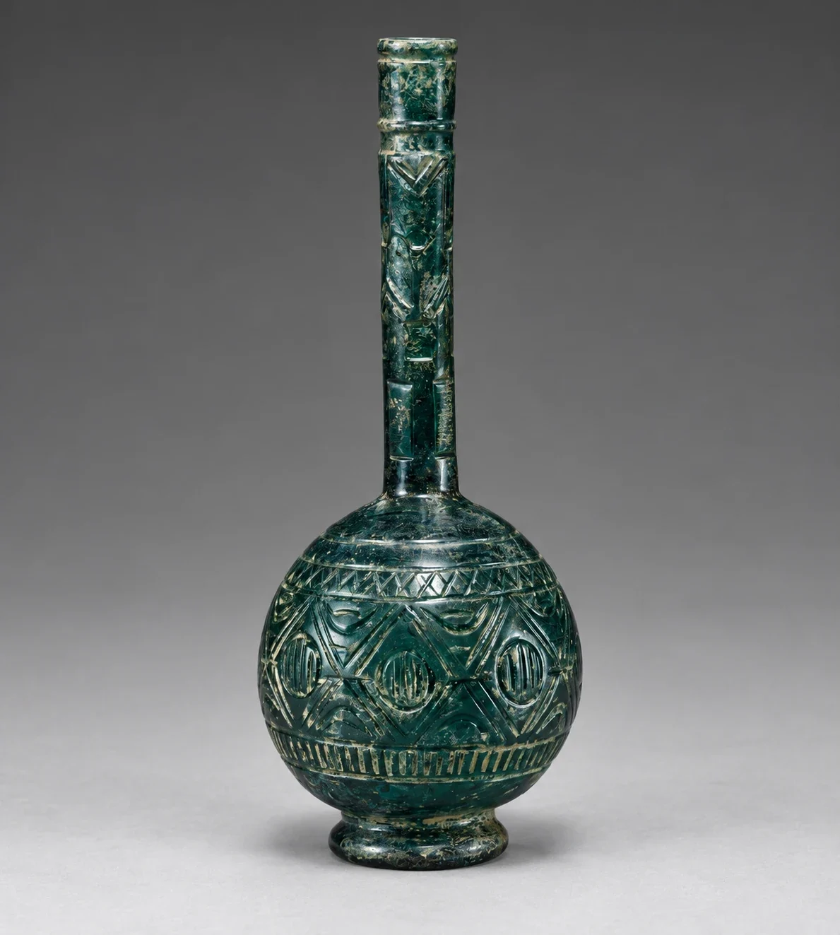 Long-necked blue-green bottle with carved bands.