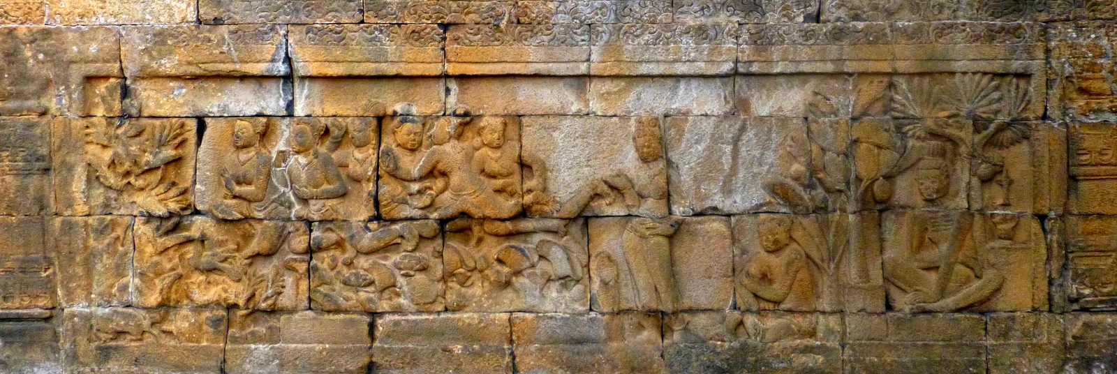 Long stone relief with flying or raised human-form maidens at left, a lotus pond below, and a captive woman, crouching hunter and ascetic beneath trees at right.