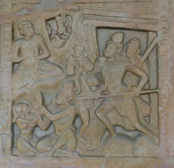 Weathered relief with a seated Buddha at upper left and armed humanlike figures gathered below and at right in an architectural setting.